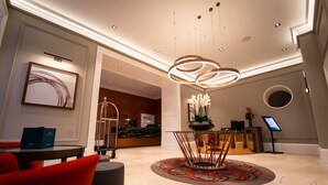 A modern lobby with a reception desk, a round table with a unique design, and a large abstract painting on the wall.