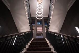 Una gran escalera de diseño moderno, con un elemento de iluminación central y barandillas negras.