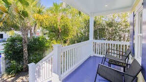 A covered porch with a white railing, a table, and two chairs. - Keys Breeze - Walk to Duval, Private Pool (Key West)