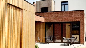 Een modern gebouw met een houten gevel en een bakstenen gedeelte.