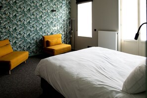 A hotel room with a large bed, a yellow armchair, a sofa, and a patterned wallpaper. - Hôtel de la Poste (Ellezelles)