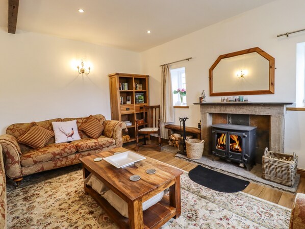 A cozy living room with a sofa, coffee table, fireplace, bookshelf, and a mirror.