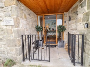 Une entrée en pierre, avec un plafond en bois, une enseigne indiquant « Angler's Barn », et un portail en métal.