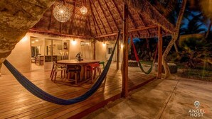 A thatched-roof structure with a dining area and a hammock.