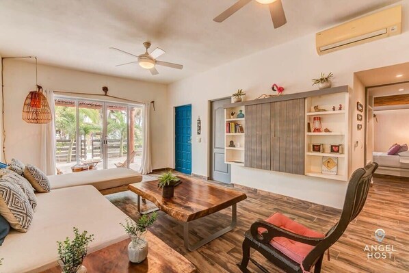 A spacious living area with a wooden coffee table, a sofa, a chair, and a bookshelf.