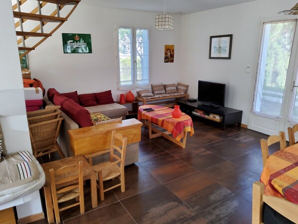 Un salon comprenant un canapé, un téléviseur, une table à manger et un escalier.