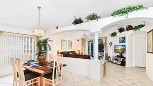 A spacious living area with a dining table, chairs, a sofa, and a TV. - Entire Villa with Pool and great Privacy near Disney (Kissimmee)
