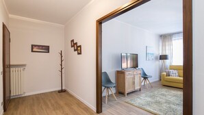 Moderni olohuone, jossa on puulattia, televisio, sohva ja sohvapöytä.
