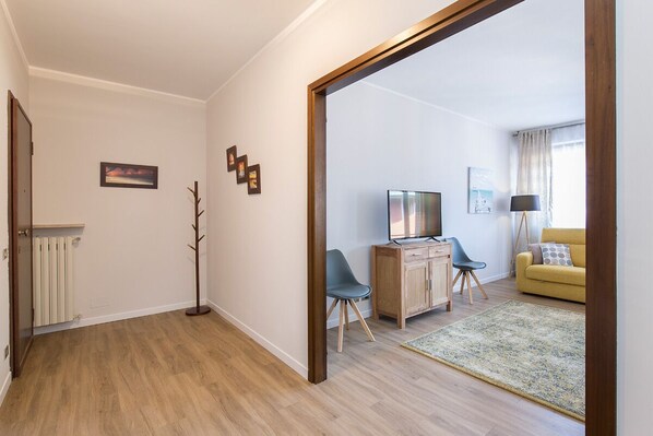 Una sala moderna con piso de madera, televisor, sofá y una mesa de centro.