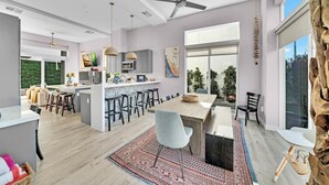 A modern kitchen with a central island, bar stools, and a dining table.