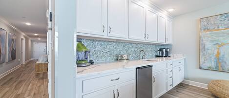 A modern kitchen with white cabinets, a tiled backsplash, and a dishwasher.
