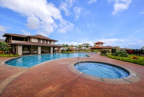 A swimming pool area with multiple pools, a covered seating area, and a building with a sloped roof. - Summer Deal Poipu Villa Near Beach with Resort Pool and Hot Tub (Koloa)