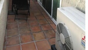 Eine Terrasse mit Tisch, Stühlen, einem Ventilator und einer Schiebetür.