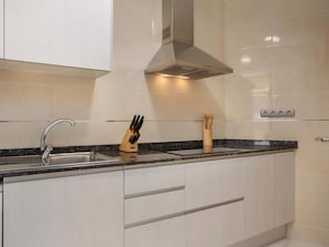 A modern kitchen with a stainless steel sink, a knife block, and a built-in stove.