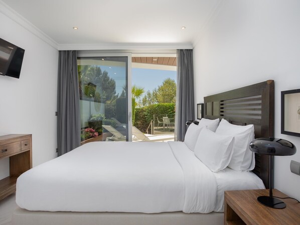 A modern hotel room with a large bed, a flat-screen TV, a bedside table, and a view of the outdoors.