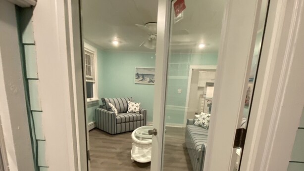 A narrow hallway leading to a living area with a sofa and a coffee table. - Cozy Cottage in Snug Harbor, minutes to the beach (pet friendly) (South Kingstown)