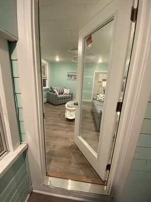A narrow hallway leading to a living area with a sofa and a coffee table. - Cozy Cottage in Snug Harbor, minutes to the beach (pet friendly) (South Kingstown)