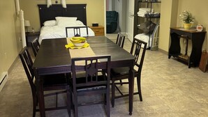 A hotel room with a large bed, a dining table with chairs, a small desk, and a chair.