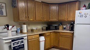 A kitchen with wooden cabinets, a white stove, a microwave, and a refrigerator.