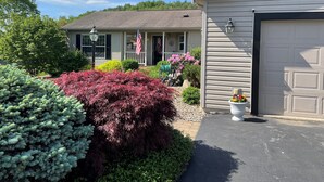 A residential house with a garage, a front porch, and a well-maintained garden with various shrubs and flowers.