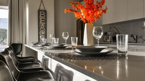 Una cocina moderna con una isla central, un jarrón con flores naranjas y un cartel con la palabra 'BEACH'.