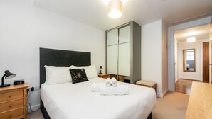 A neatly arranged bedroom with a bed, bedside tables, a mirror, and a walk-in closet.