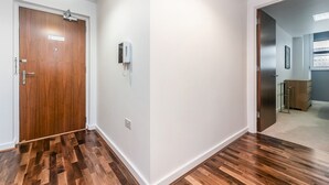 A hallway with wooden flooring, a door with a 'No Smoking' sign, and a wall-mounted phone.