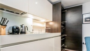 A modern kitchen with white cabinets, a black kettle, and a toaster.