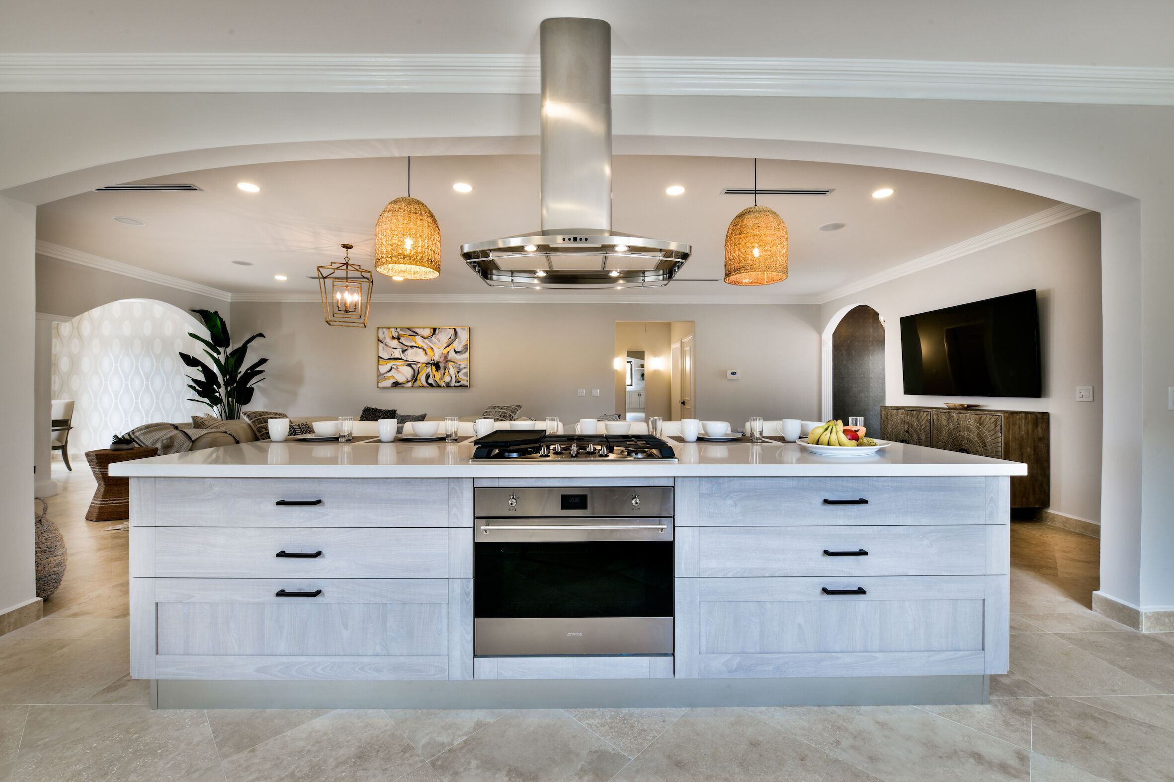 A modern kitchen with a large island, stainless steel appliances, and pendant lighting.