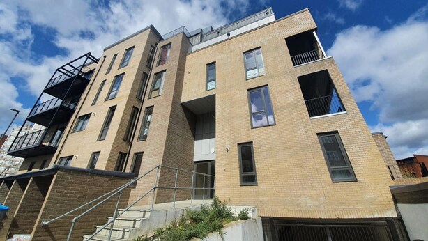Un immeuble à plusieurs étages, doté d’une façade en briques, de grandes fenêtres et d’un escalier menant à l’entrée.