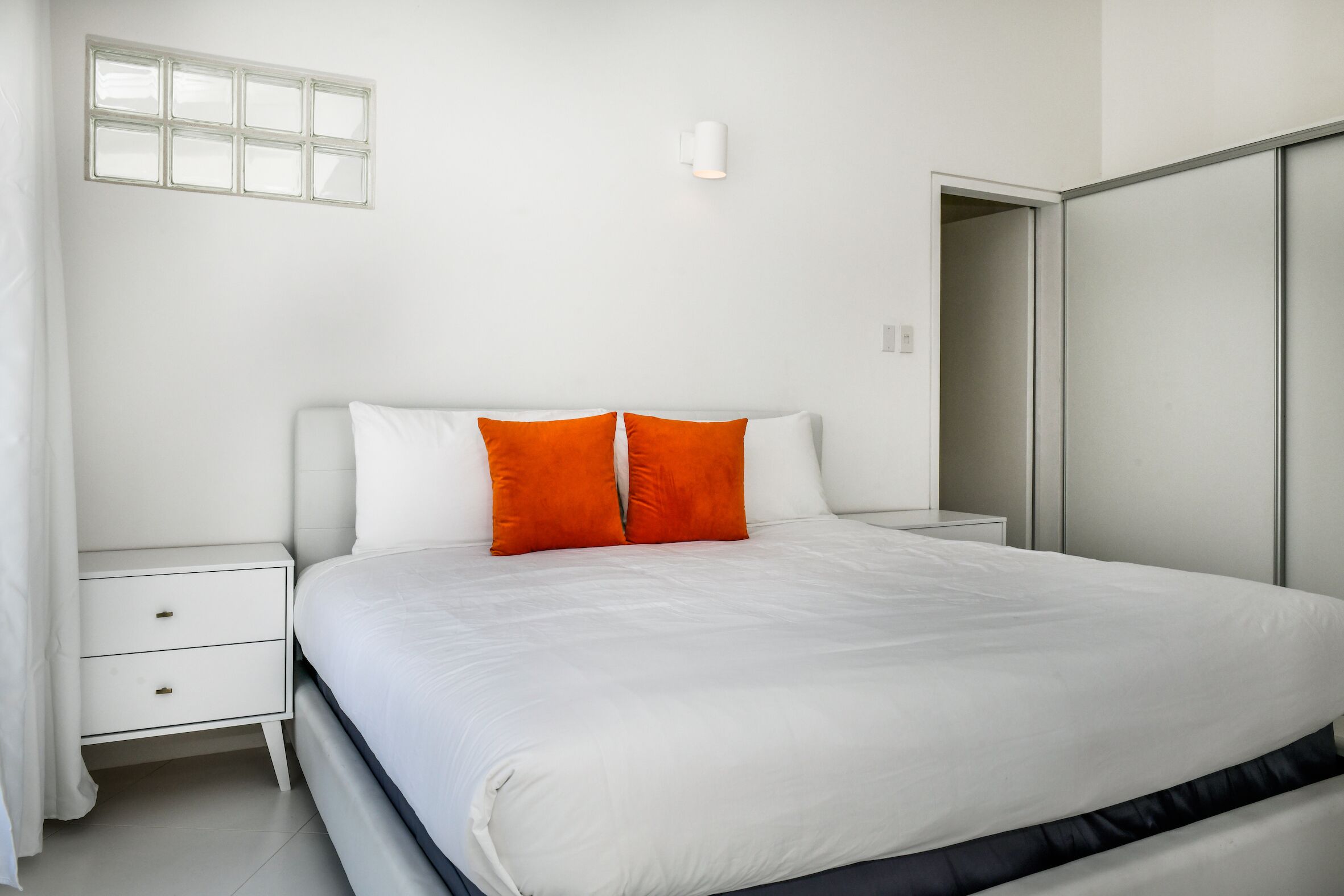 Ein Schlafzimmer mit einem Bett, einem Nachttisch in Weiß und einem Kleiderschrank.
