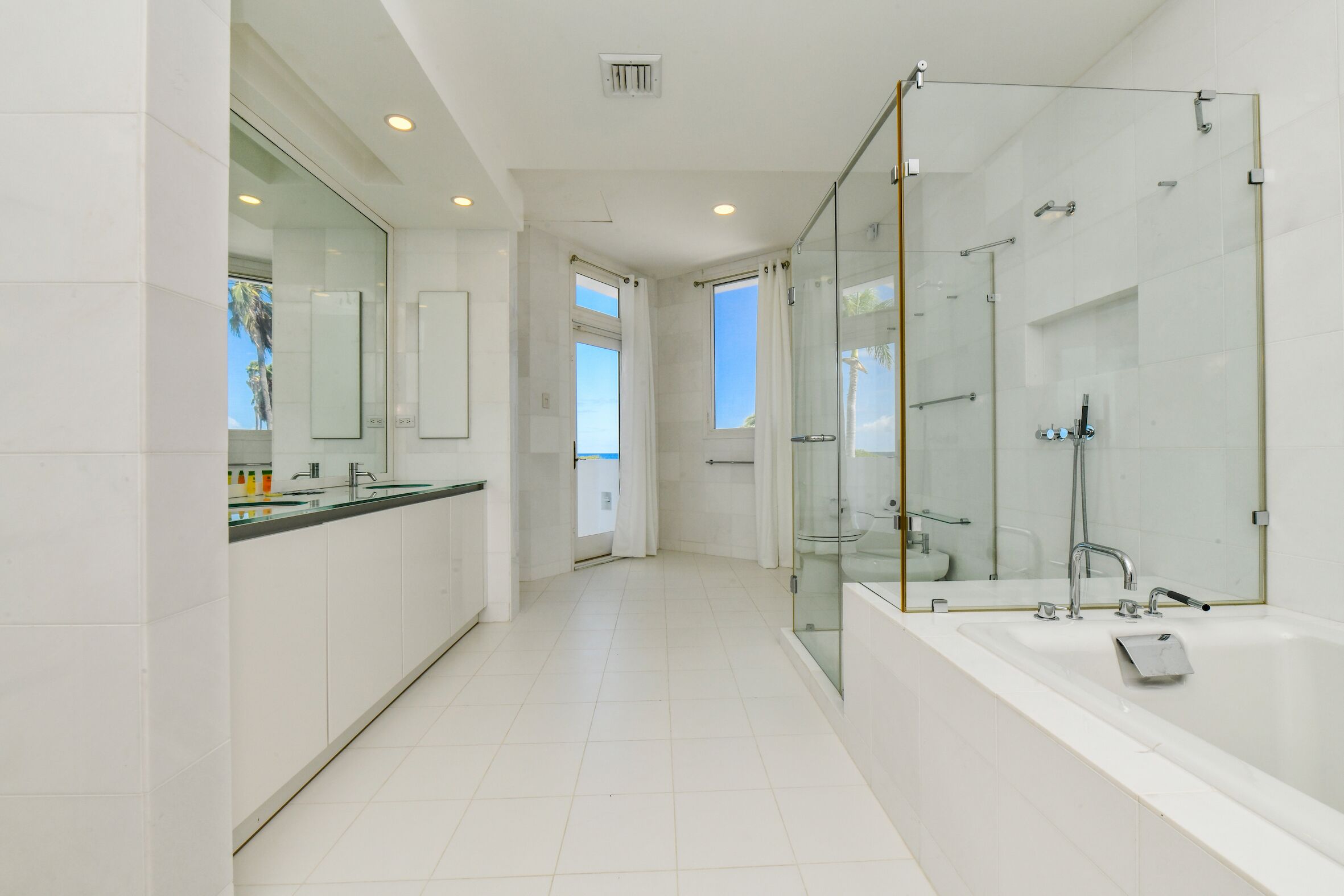 Un baño moderno con ducha envuelta en vidrio, una bañera grande y un tocador con espejo.