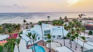 Un resort moderno con piscina, palmeras y vistas al océano.
