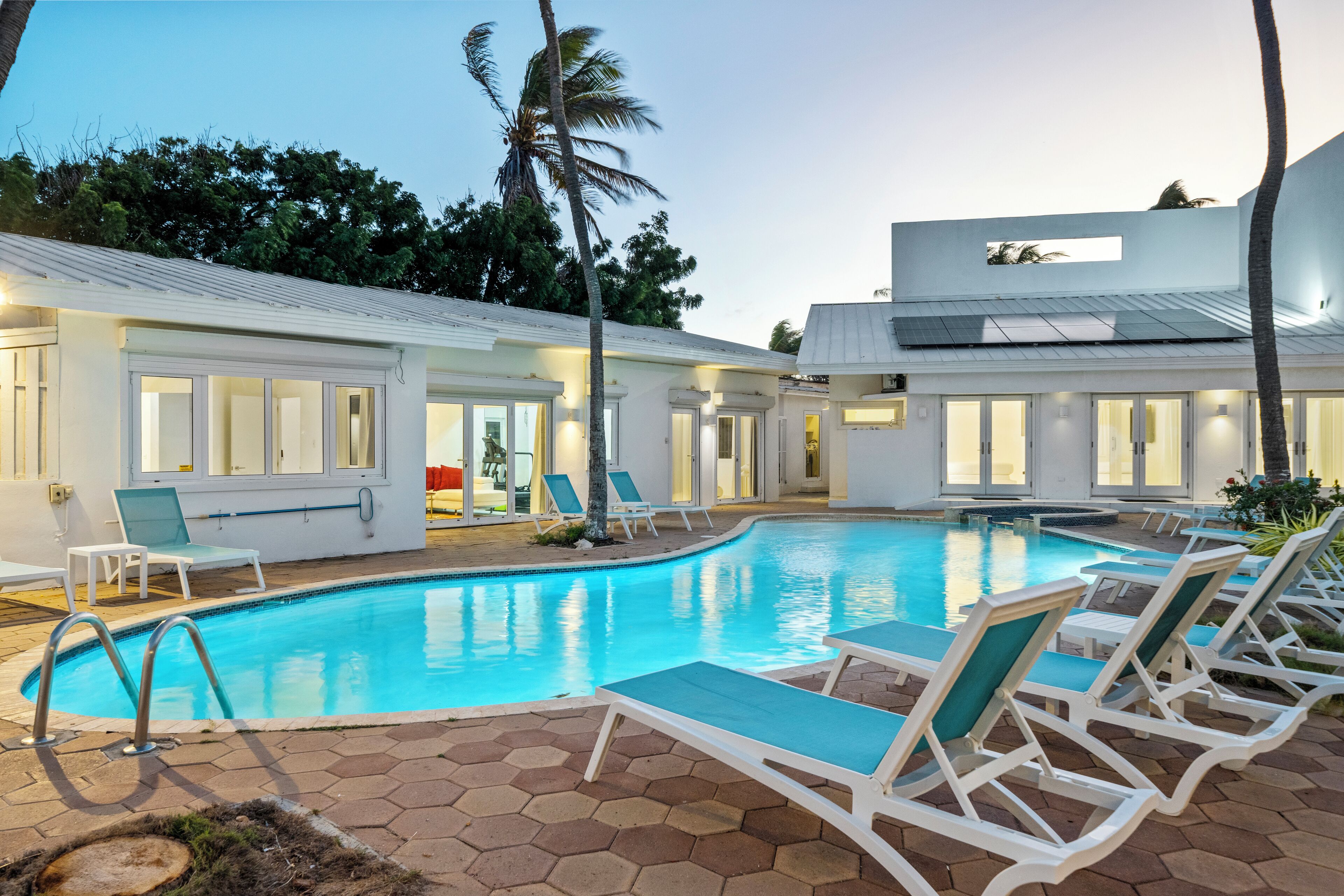 A swimming pool with lounge chairs and a building with large windows.