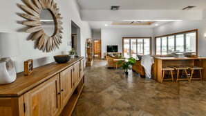 Un espacio habitable amplio con un mueble de madera, un espejo decorativo y un gran ventanal que proporciona luz natural.