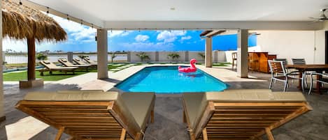 A pool area with lounge chairs, a table, and a ceiling fan.