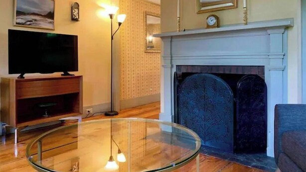 A living room with a fireplace, a television, and a glass table. - Maple Suite- Private  Ground Floor Apartment in front of Smith College (Northampton)