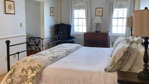 A bedroom with a bed, a chair, a dresser, and two windows with curtains. - Maple Suite- Private  Ground Floor Apartment in front of Smith College (Northampton)
