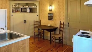 A compact kitchen with a wooden table, two chairs, a microwave, and a stove. - Maple Suite- Private  Ground Floor Apartment in front of Smith College (Northampton)