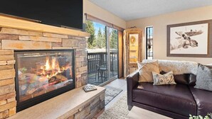 A living room with a fireplace, a sofa, and a large window.