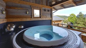 Una cabaña de madera con jacuzzi y vistas del paisaje circundante.