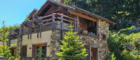 Una cabaña rústica con fachada de piedra, balcones de madera y tejado de paja.