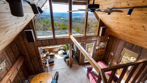 A wooden cabin with a dining area, seating, and a view of the landscape.