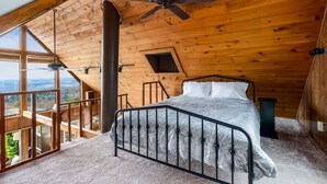 A bedroom with a bed, a ceiling fan, and a view of the outdoors.