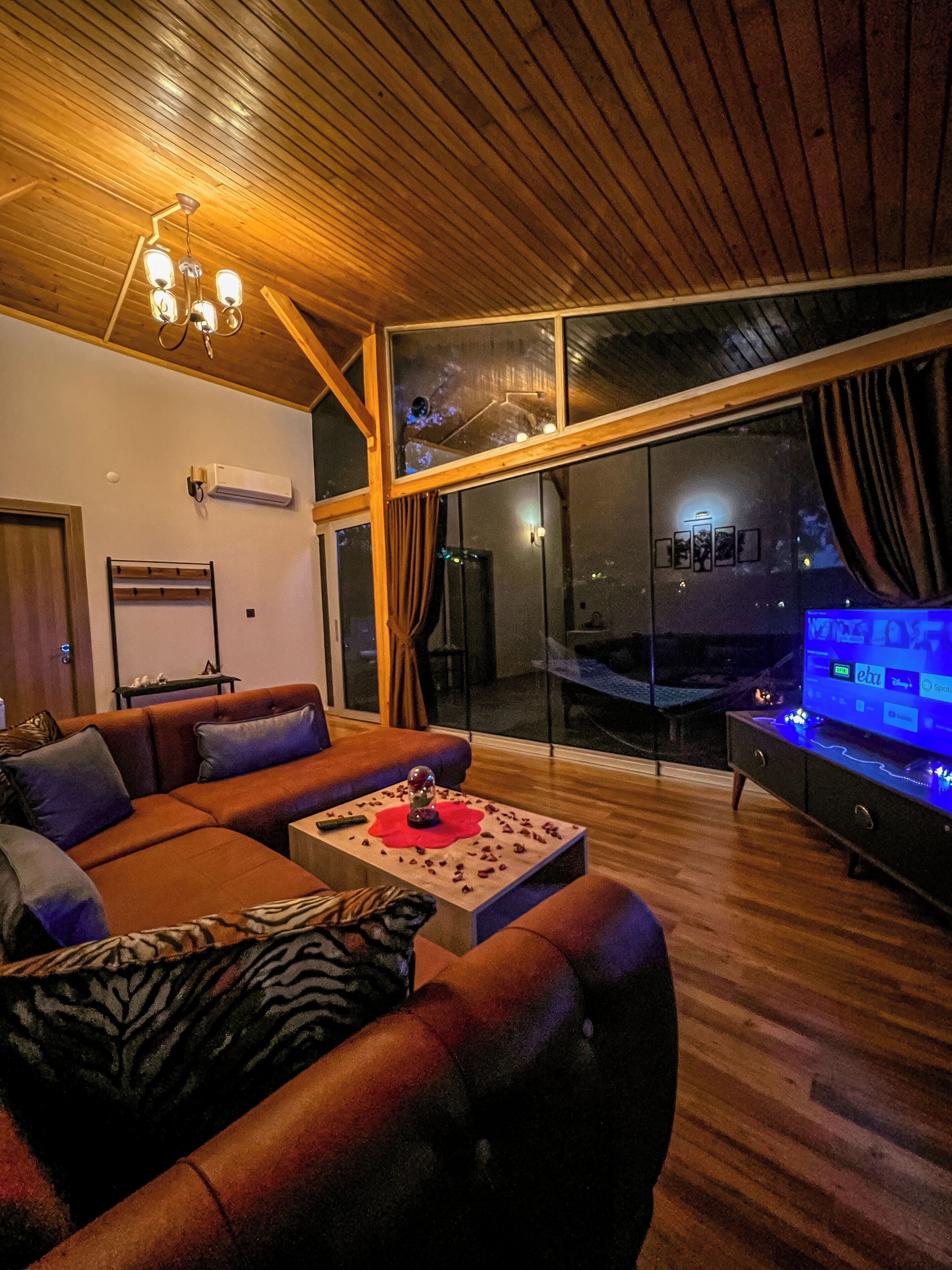 Ein modernes Wohnzimmer mit Holzboden, einem großen Sofa, einem Couchtisch und einem Fernseher.