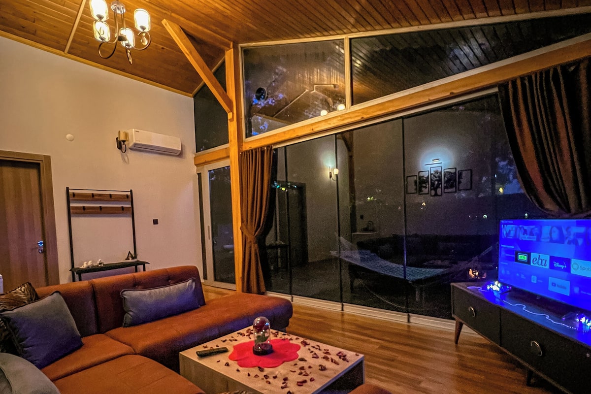 Ein modernes Wohnzimmer mit Holzboden, einem großen Sofa, einem Couchtisch und einem Fernseher.