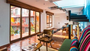 A spacious living area with a large sliding glass door leading to a balcony, a ceiling fan, and a colorful sofa. - Unique 2BR Suite at the Best Location in Sayulita (Sayulita)