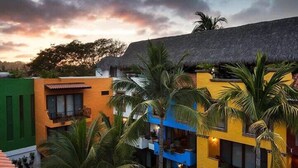 A multi-story building with a thatched roof, surrounded by palm trees. - Unique 2BR Suite at the Best Location in Sayulita (Sayulita)