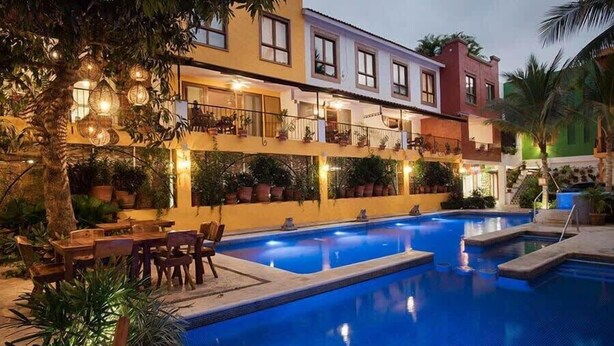 A swimming pool area with a dining setup and potted plants. - Unique 2BR Suite at the Best Location in Sayulita (Sayulita)