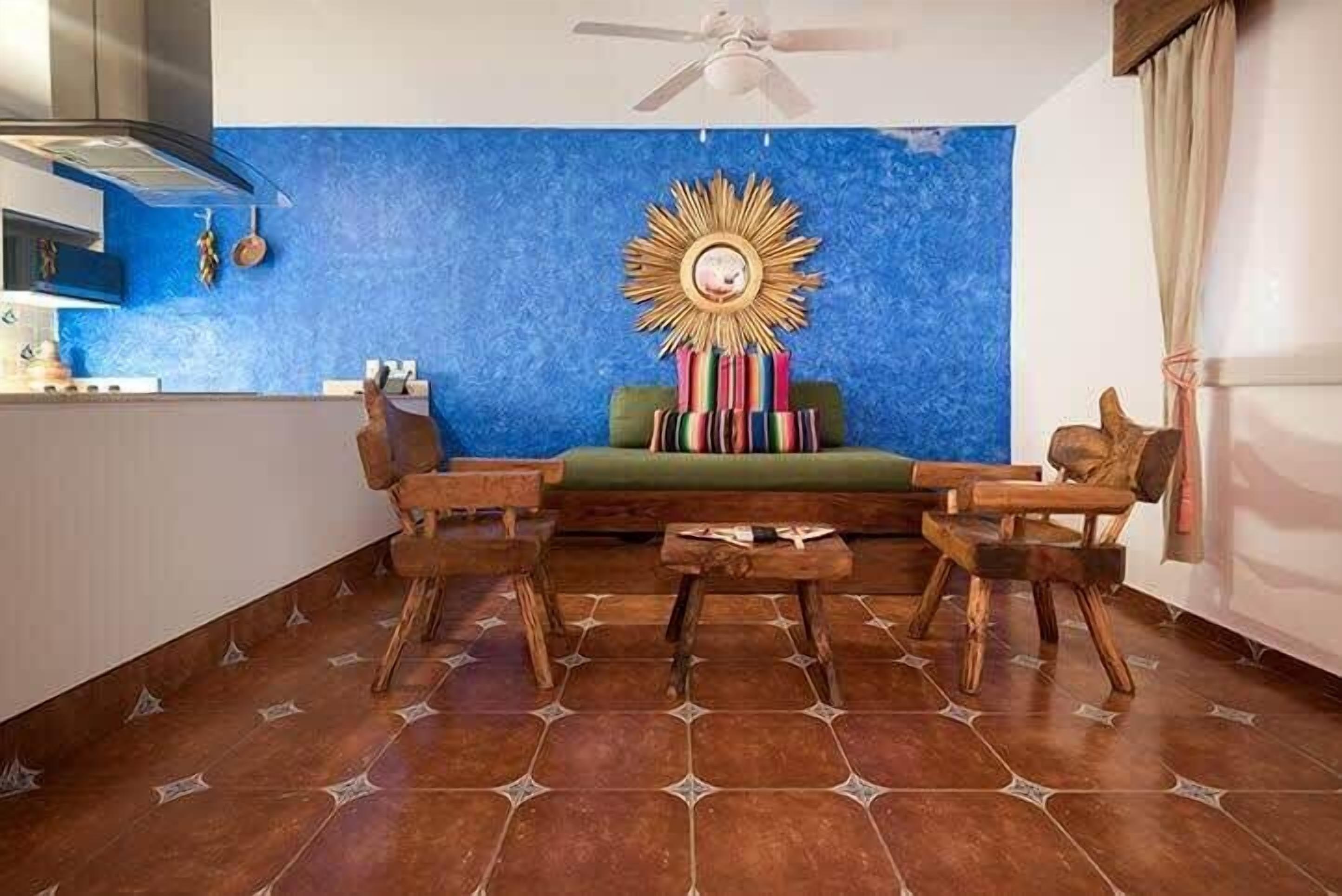 A room with a blue wall, a wooden sofa, and a ceiling fan.